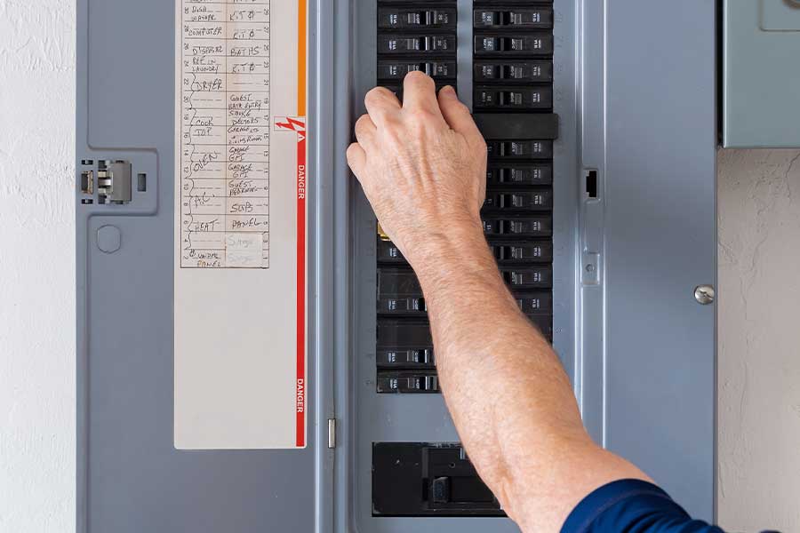 Emergency electrician inspecting a circuit breaker panel in Raleigh, NC