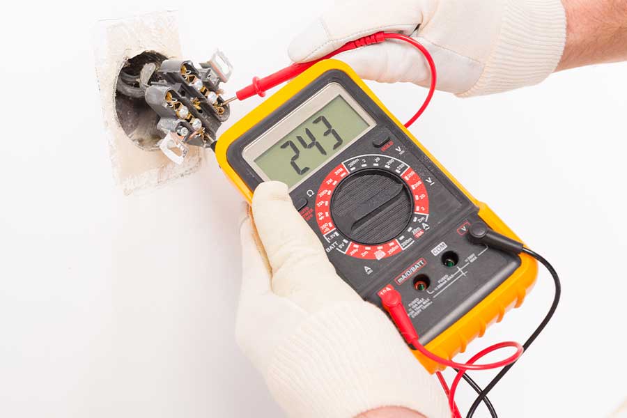 Emergency electrician using a voltage meter to troubleshoot an outlet