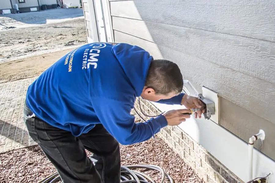 Electrician repairing an outdoor electrical outlet at a home in Clayton, NC